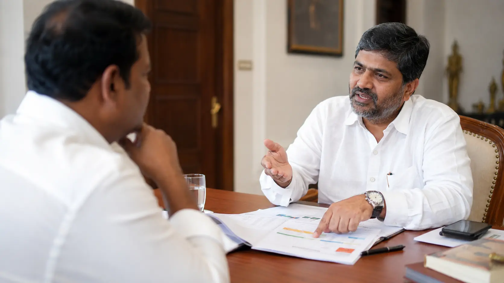 Candidate in conversation with a political strategist reviewing a strategy document in a meeting room